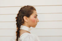 a woman wearing a white shirt and a braided hairstyle