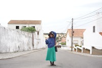 a woman in a long skirt standing on a street