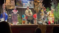 a group of people dressed in native costumes on stage
