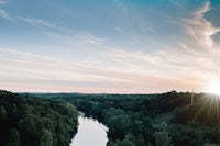 the sun is setting over a river in a forest