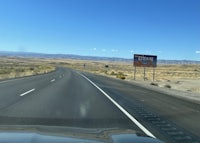 a car driving down a highway with a sign in the distance