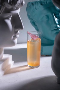 a drink is sitting on a table next to some statues