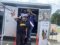 a group of men standing in front of a food truck