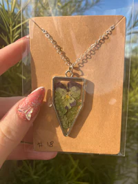 a person holding a necklace with a flower in it