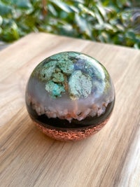 a glass sphere with green and brown rocks inside