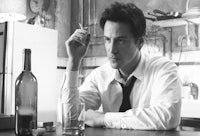 a man sitting at a table with a bottle of wine