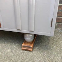 a grey cabinet with wooden legs on the ground