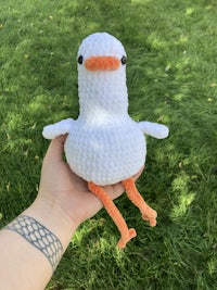 a person holding a crocheted white goose