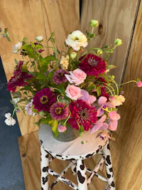 a vase of flowers sitting on a wooden stool