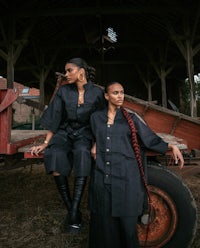 two women in black clothes posing in front of a tractor