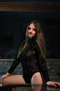 a woman in a black bodysuit posing on a table
