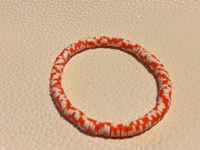 an orange and white striped bracelet on a table