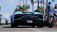 a blue lamborghini is parked on a street in front of a crowd of people