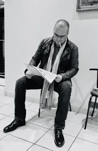 a man sitting on a chair reading a newspaper