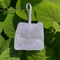 a white embroidered ornament with the word tilly time on it