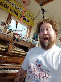 a man with a beard in front of a piano