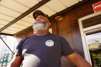 a man with a beard standing outside of a restaurant