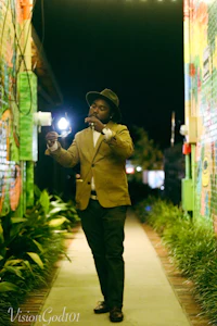 a man in a hat and suit walking down a sidewalk