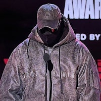 a man in a hooded jacket is standing on stage