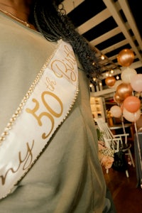 a woman wearing a sash with the words 50 the bride