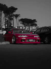 a black and white photo of a red car parked in a parking lot