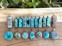 a group of turquoise stone pendants on a wooden table
