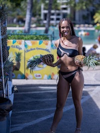 a woman in a bikini holding pineapples