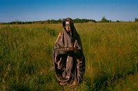 a woman in a robe standing in a field