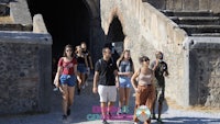 a group of people walking through a stone archway