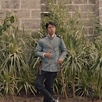 a man in uniform standing in front of plants