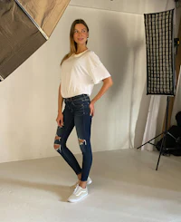 a woman in ripped jeans standing in front of a studio light