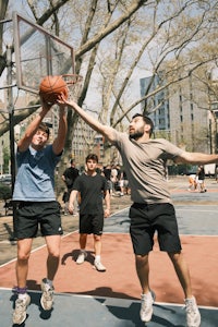 a group of men playing basketball in a park